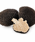 Whole and cut Fresh Black Summer Truffles showing the pale brown marbled interior of Tuber aestivum EXTRA Grade